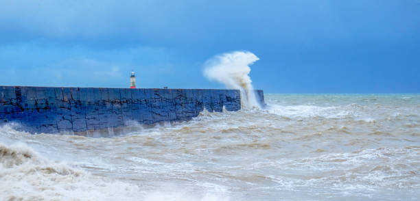 uma parede do porto com um mar tempestuoso áspero batendo contra a parede fazendo com que o mar fique embaçado e em movimento - lighthouse storm sea panoramic - fotografias e filmes do acervo