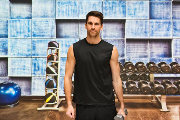 männlicher instruktor macht entspannungsübung im fitnessstudio im fitnessstudio mit tanktop und aktiv mit handgewicht und fitnessball - 11311 stock-fotos und bilder