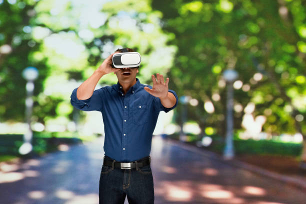 istock Caucasian young male standing in front of public park and using virtual reality 1203431019