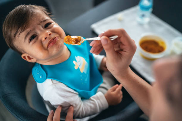 Trying to feed a baby boy Mother feeding the cry baby son with a spoon refusing photos stock pictures, royalty-free photos & images