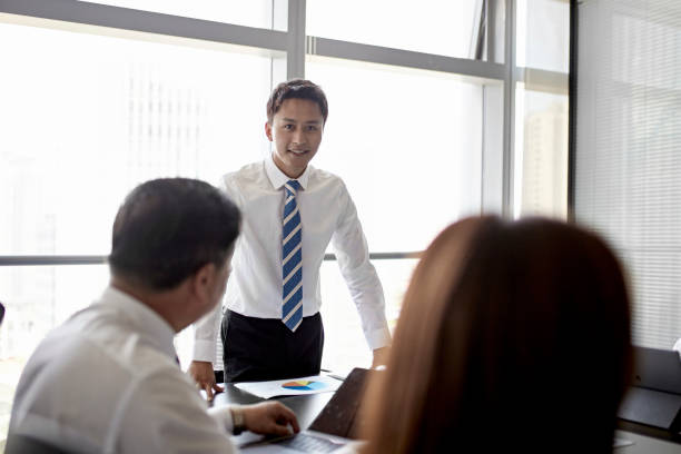 istock Smiling Young Chinese Businessman Giving Presentation 1203435412