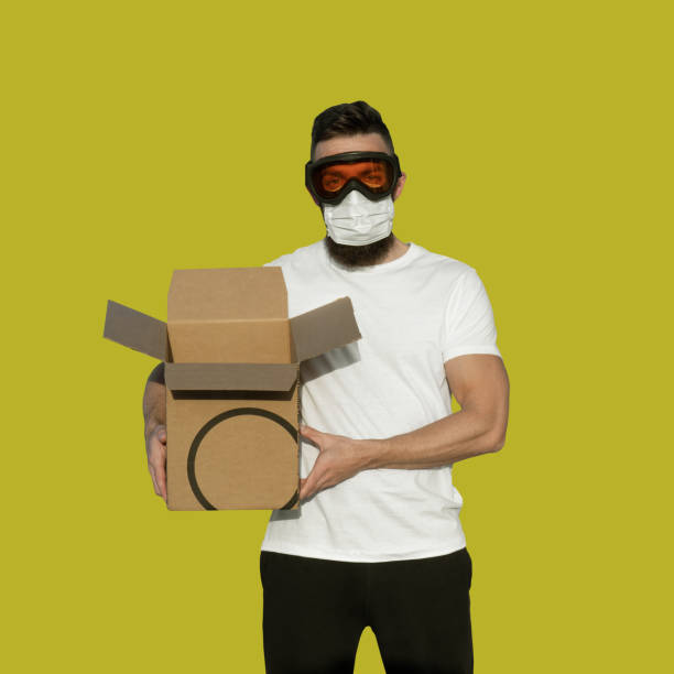 istock Man in protective goggles and surgical mask delivered cardboard 1203436895