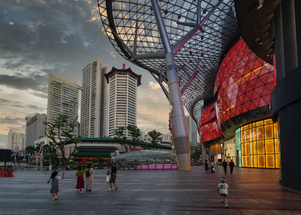 Singapore, January 2020.  Some people walk in front of the stores of ION Orchard shopping mall at sunset