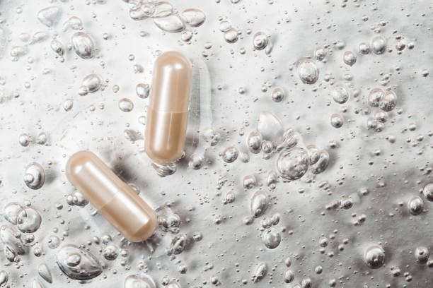 capsula di bellezza sullo sfondo con bolle di ossigeno cosmetiche - chinese medicine herb pill nutritional supplement foto e immagini stock