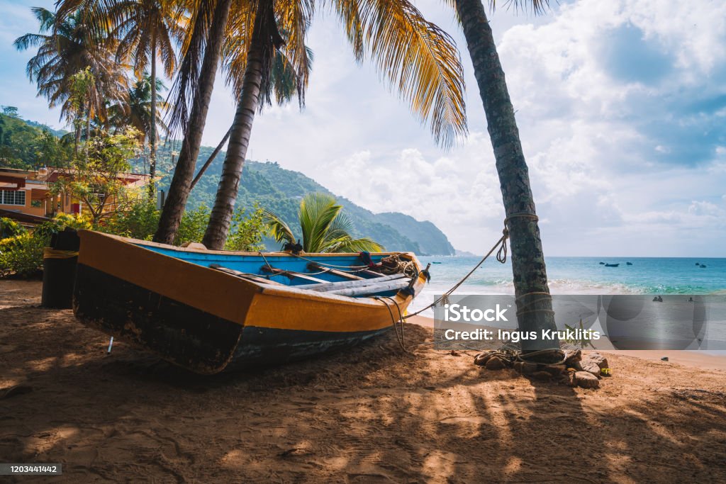 Colorful fishing boat near the transparent and clear turquoise water on a remote paradise island. Colorful fishing boat near the transparent and clear turquoise water on a remote paradise island. Summer vibe spirit. Local fishermen tool. Trinidad - Trinidad And Tobago Stock Photo