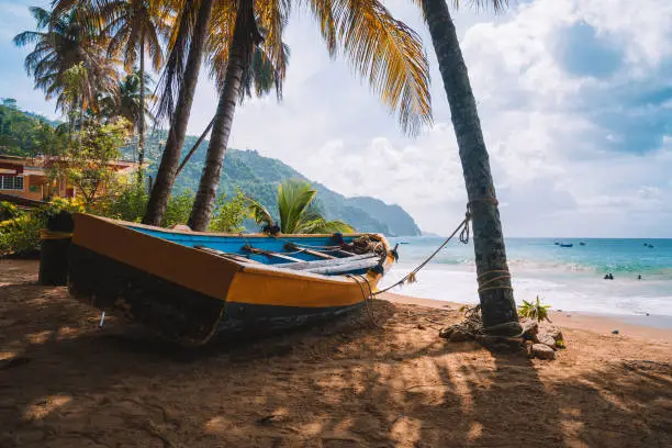 Colorful fishing boat near the transparent and clear turquoise water on a remote paradise island. Summer vibe spirit. Local fishermen tool.