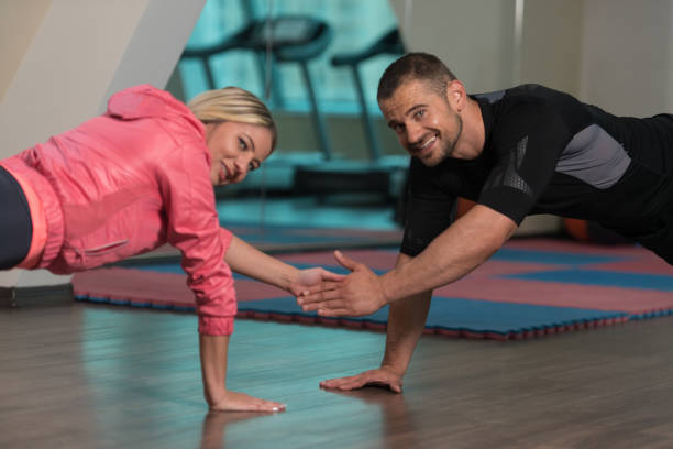 istock Young Couple Doing Push-Up Exercise In The Gym 1203441708