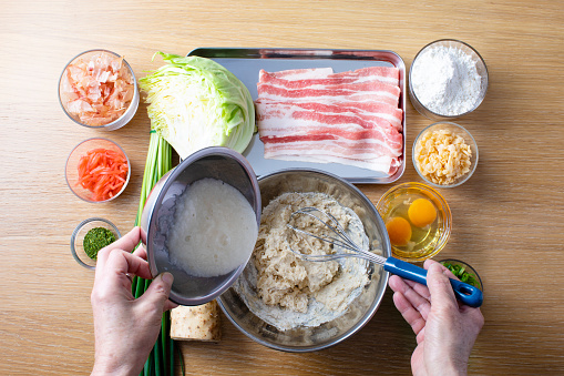 Japanese okonomiyaki recipe. Mix flour, egg, cabbage, pork, and tempura and bake on an iron plate. Sprinkle with sauce, mayonnaise, seaweed and ginger.