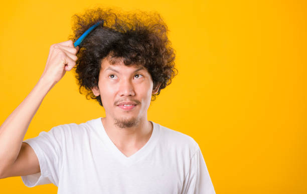 istock Asian man combing curly hair on yellow background 1203448627