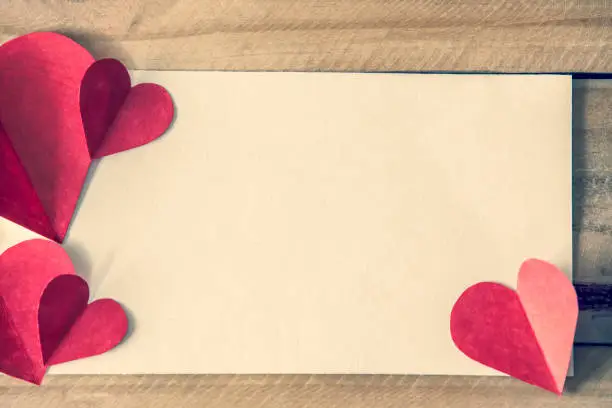 Valentine's day red hearts with blank notepad on brown wooden table