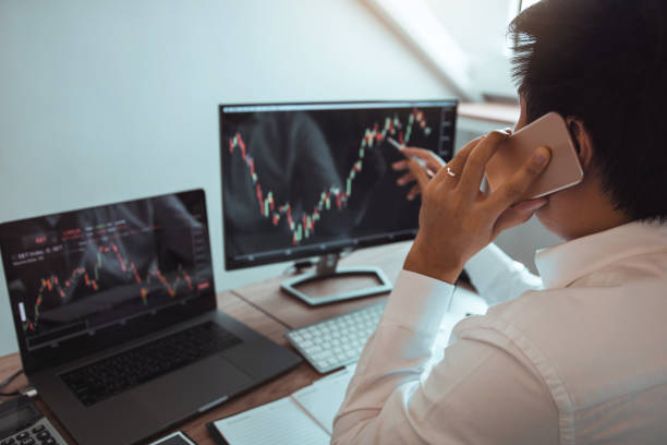 istock Agent trader man talking at telephone and checking business stock data on computer in office room. 1203465571