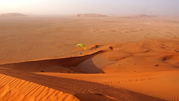Paraglider preparing to and flying over the amazing sand dunes in the Rub al Khali desert in Oman