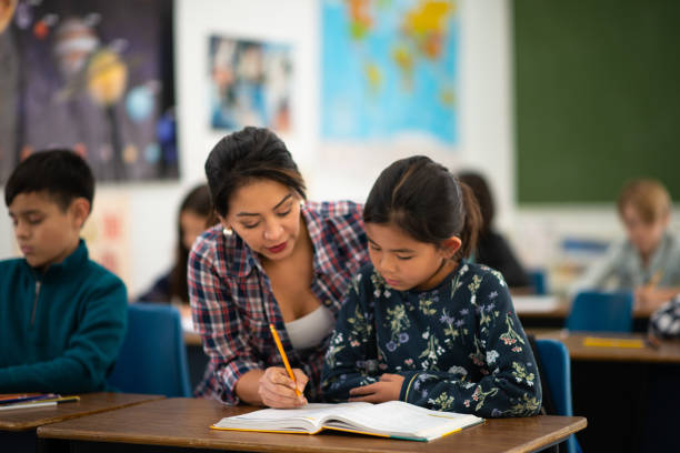 istock Female Teacher Helping an Elementary Student In Class stock photo 1203472533