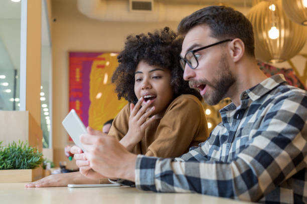 istock Man and woman looking on gadget screen with surprise 1203474897