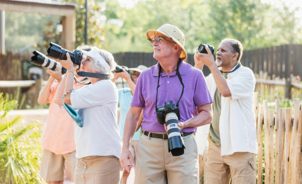 istock Mature man with senior tour group, taking photos 1203477626