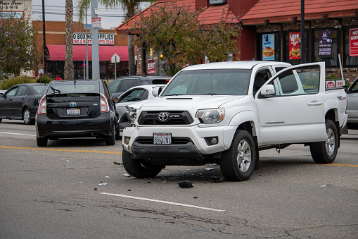 Van Nuys, California / USA  - January 19, 2020: A white Toyota Tacoma truck sits in the middle of the road after an accident in front of 6750 Balboa Blvd, viewed from the front. There were no injuries but three vehicles were involved.