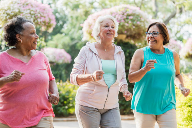 Multi-ethnic senior women exercising together A multi-ethnic group of three senior women, in their 60s, hanging out together at a park, exercising. They are running, jogging or power walking side by side, smiling and conversing. 60 69 years stock pictures, royalty-free photos & images