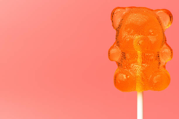 сахарный леденец. крупным планом карамель леденец на палке в форме медведя на розовом фоне - flavored ice lollipop candy affectionate стоковые фото и изображения