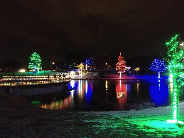 istock Christmas lights on trees at night in a park with reflection on lake with a bridge 1203482129