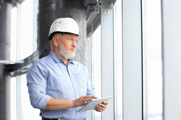 istock Mature architect wearing hardhat inspecting new building. 1203487570