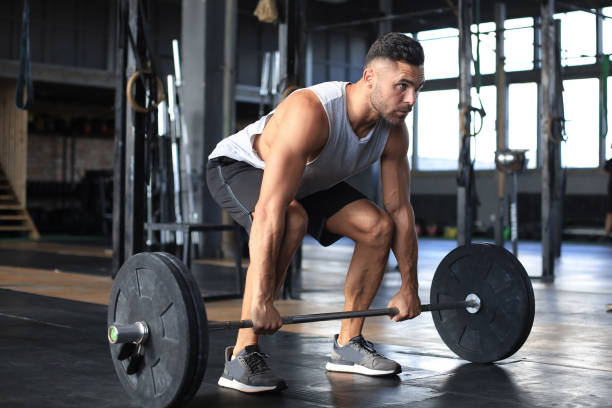 istock Muscular man working out in gym doing exercises with barbell at biceps. 1203487859