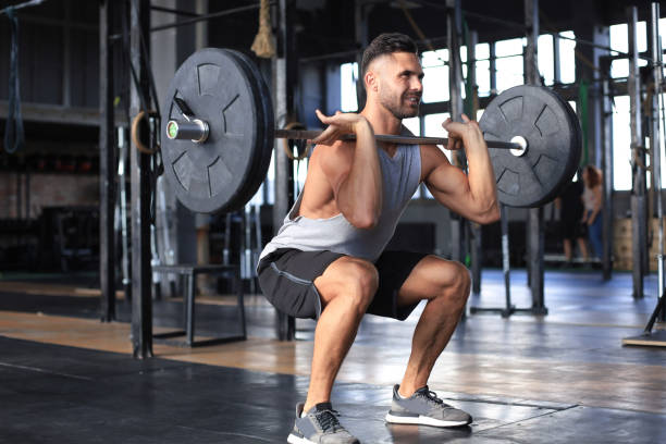 istock Muscular man working out in gym doing exercises with barbell at biceps. 1203487969