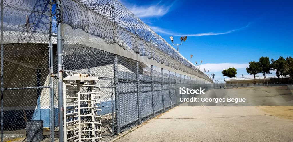 Jailhouse blue sky Prison fences and turnstile of Mira Loma Detention Center in Lancaster California. Prison Stock Photo