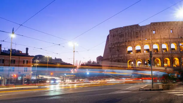 Photo of Colosseum at night with colorful blurred traffic lights