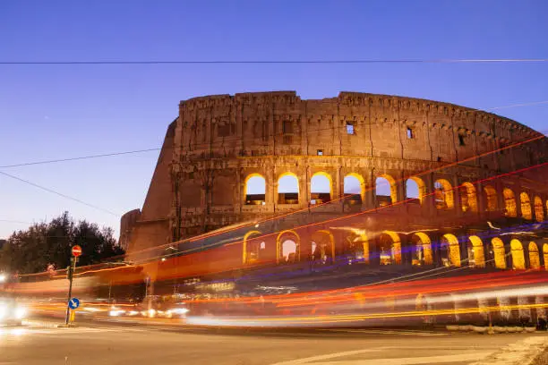 Photo of Colosseum at night with colorful blurred traffic lights