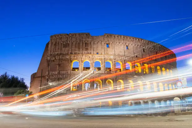 Photo of Colosseum at night with colorful blurred traffic lights