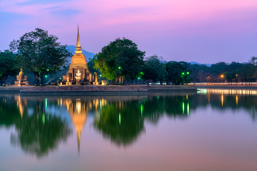 Ancient Thai temple with water reflection at Sukthai historical park at dusk