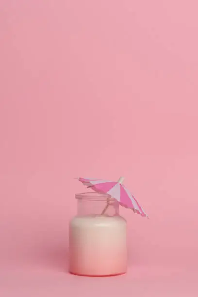 Photo of Milkshake with berry syrup in a glass jar isolated on a pink background.