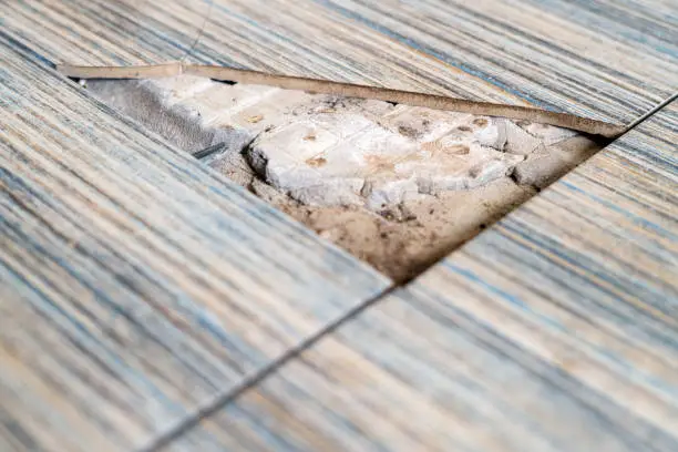 Photo of Close up view of broken tile in the bathroom. Cracked asbestos floor tile. Damaged ceramic tile background