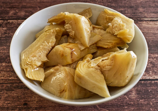 Pickled artichokes in white bowl on wooden table Pickled artichokes in white bowl on wooden artichoke stock pictures, royalty-free photos & images