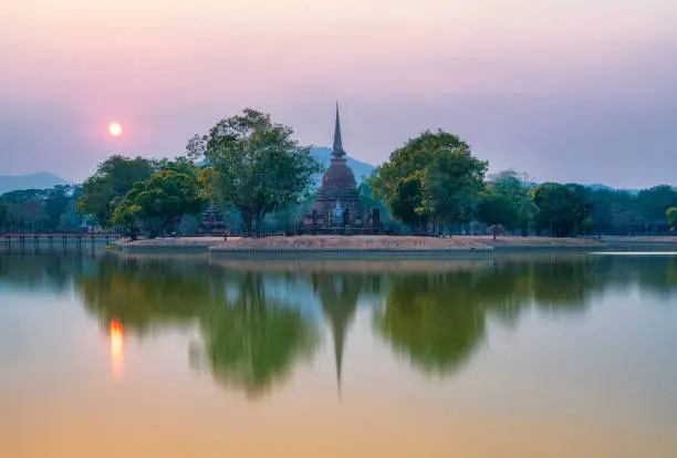 Ancient Thai temple with water reflection during sunset at Sukhothai historical park