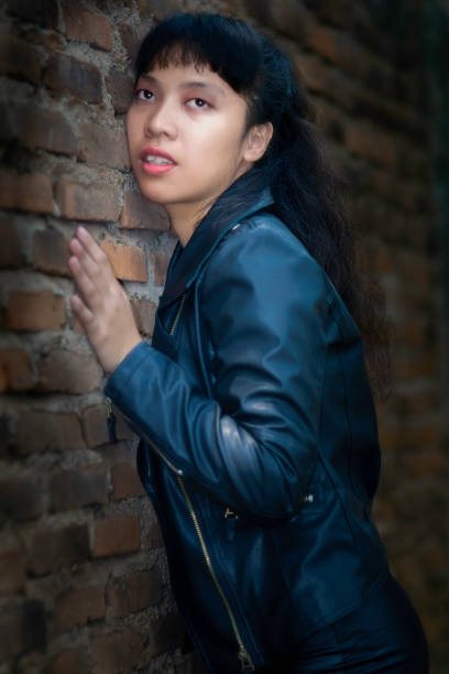 Indonesian young girl standing by an old brick wall