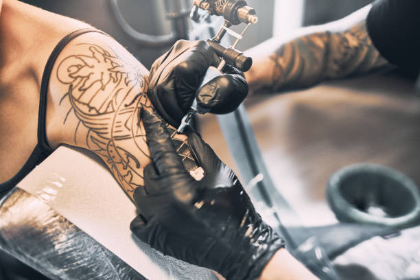Artist Tattooing woman's shoulder