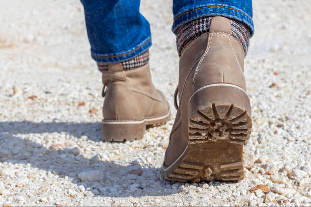 istock PU leather boots close up, rear view. Boots with tread on white rocky path. 1203507290