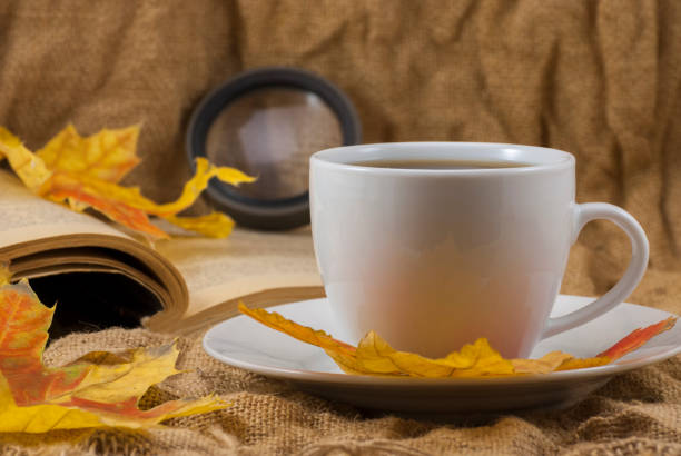 istock Coffee mug, autumn fall leaves with book on autumn background. close up 1203508334