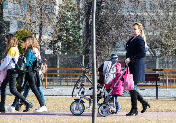 Young mother with baby stroller on the park. A sunny day in February. Central Park, USA, New York. February, 01, 2020