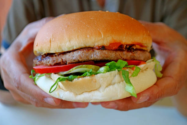 istock Closeup a tasty and big hamburger held in hand 1203510376