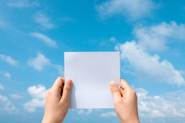 istock Woman hands holding white paper with blue sky and cloud background. 1203511462