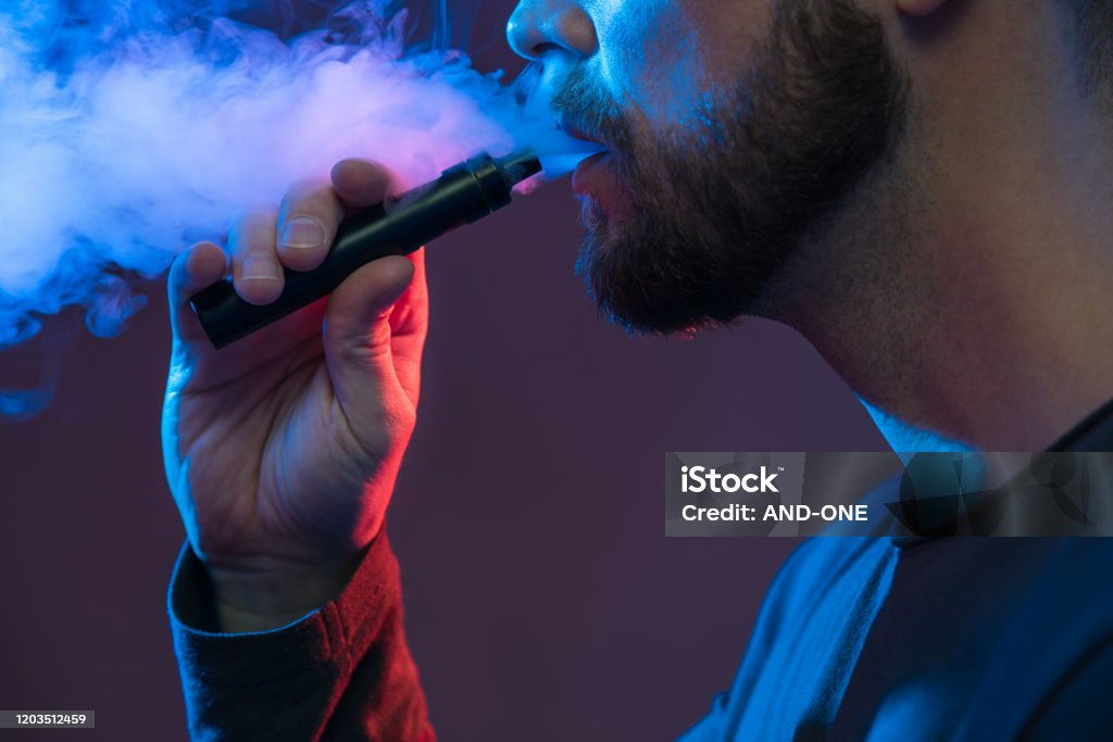 Vaping e-liquid from an electronic cigarette Vaping flavored e-liquid from an electronic cigarette Electronic Cigarette Stock Photo