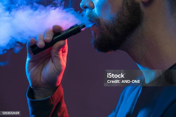 Vaping Eliquid From An Electronic Cigarette Stock Photo - Download Image Now - Electronic Cigarette, Pen, Men