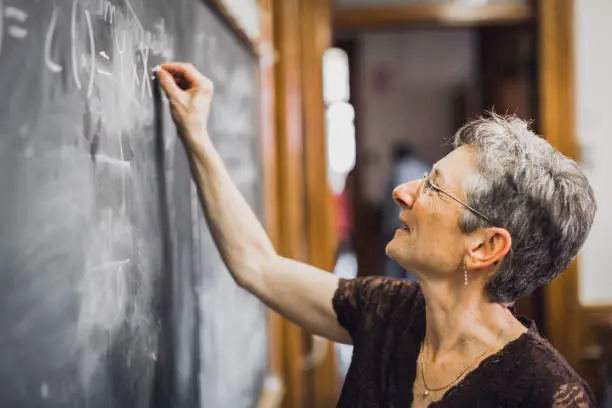 Eureka!! A happy concentrated senior female mathemathics professor found a solution, writing down a formula to the chalkboard. Personal Perspective, Selective focus. Natural interior light. Lunenburg, Nova Scotia, Canada.