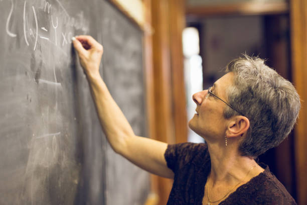 istock Senior Female Mathemathics Professor at Chalkboard Writing Formula 1203516767