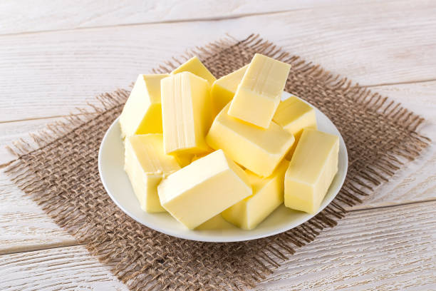 istock Rectangular pieces of fresh yellow butter on a white saucer over a white wooden table. Dairy. Sandwich butter. Natural fat nutrient. 1203519127