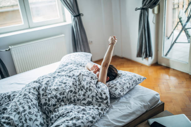 istock Sleepy woman lying in bed stretching 1203519779