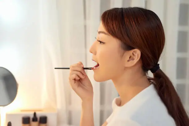 Beautiful Woman With Beauty Face Applying Lip Balm, Lipcare Stick On. Lips skincare cosmetics concept.