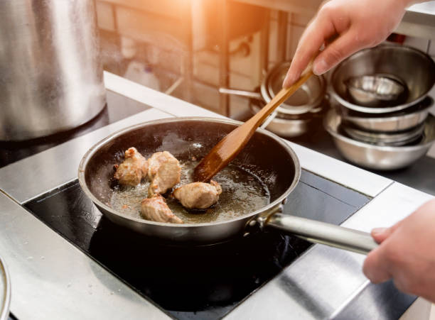 istock Chef cooks fried potatoes with pieces of meat in a restaurant kitchen 1203522932